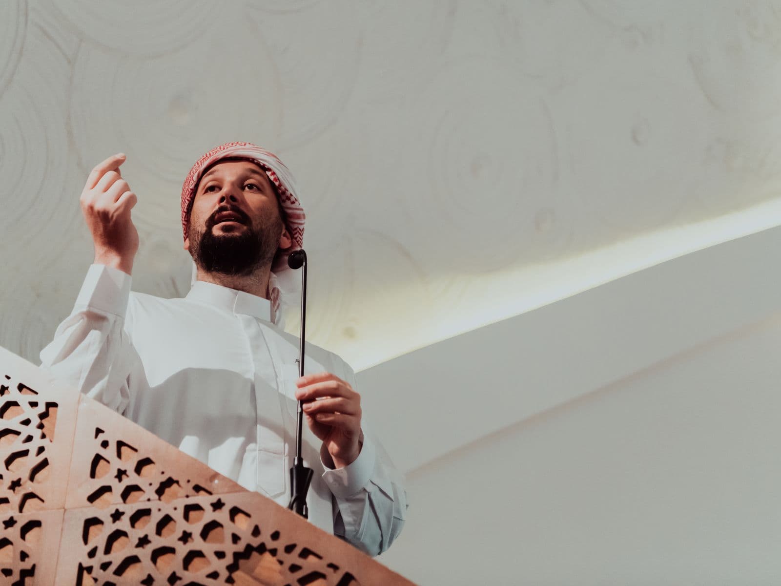 An imam giving the Friday sermon from a carved wooden pulpit