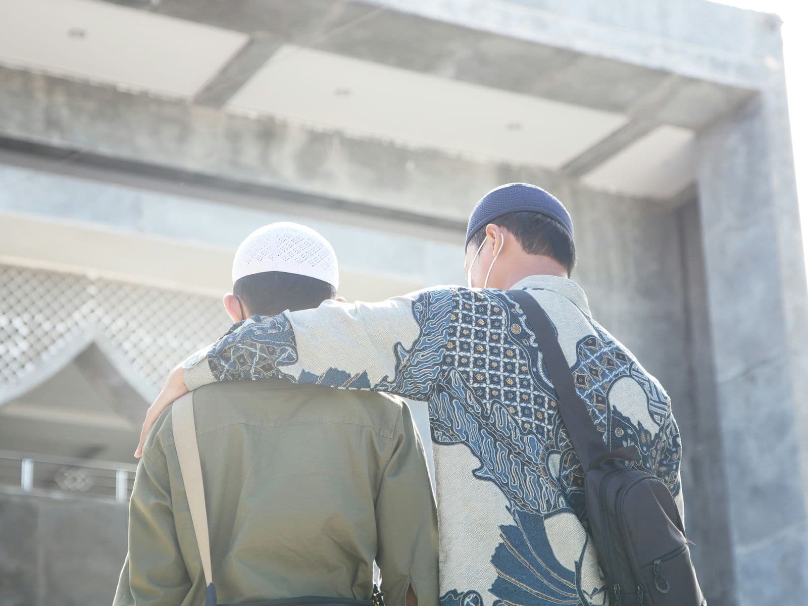 Two men walking toward a mosque, one with his arm around the other's shoulder